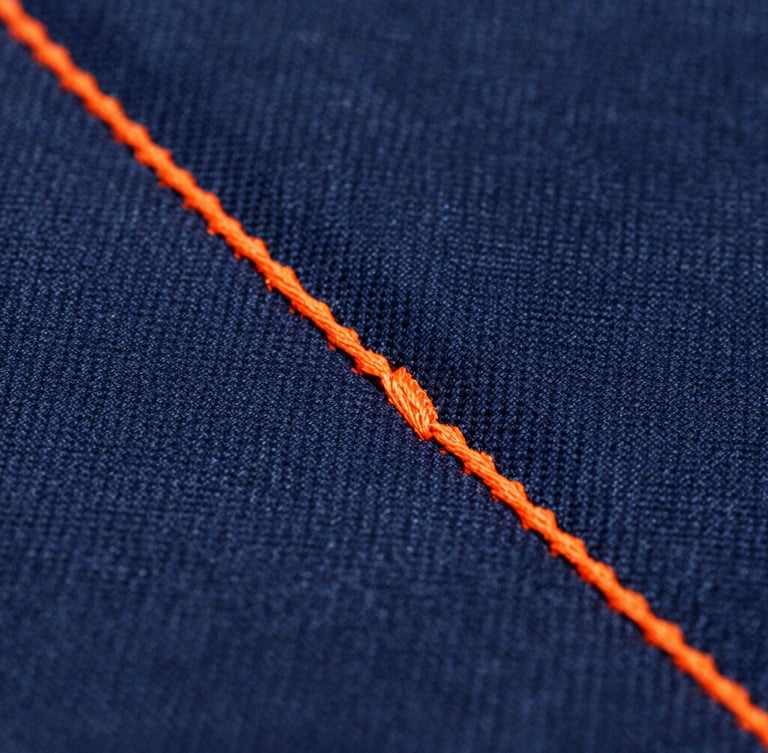 Macro shot of heavy-duty triple-stitching on a deep navy canvas fabric, safety orange thread, industrial quality, crisp focus
