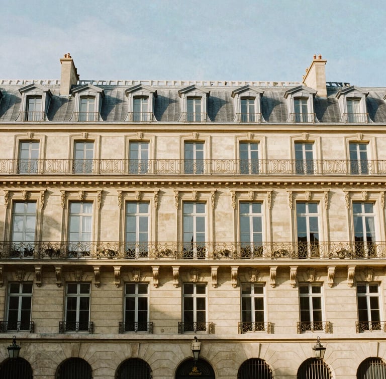 Wide architectural shot of a classic Haussmannian facade in Paris, sunlit warm afternoon light, soft shadows, 35mm lens editorial photography