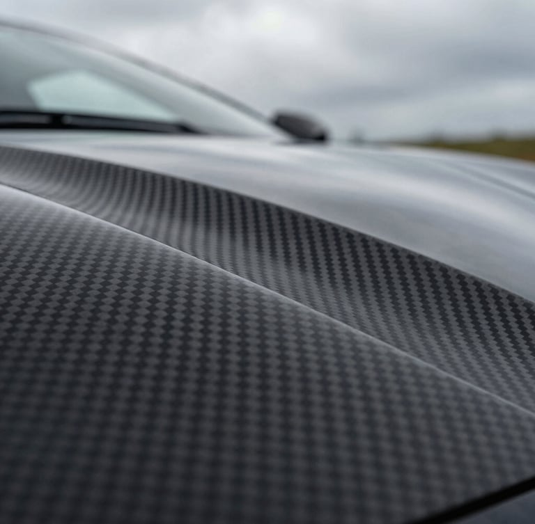 Extreme close-up of a hypercar's carbon fiber weave panel under dramatic overcast daylight, sharp lines, ultra-premium texture.