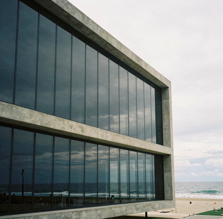 Wide architectural shot of a modern minimalist concrete and glass facade in Balneário Camboriú, soft overcast coastal daylight, ocean reflection on glass, medium format film