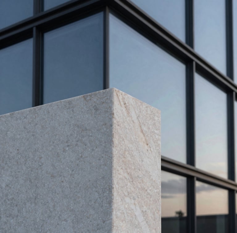 Close-up architectural detail of raw travertine marble and dark structural glass reflecting a twilight sky, sharp angles, clean lines, minimalist luxury.