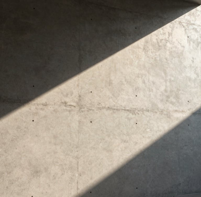 Architectural detail of a sunlit concrete wall casting sharp diagonal shadows, minimal and clean, warm afternoon light.