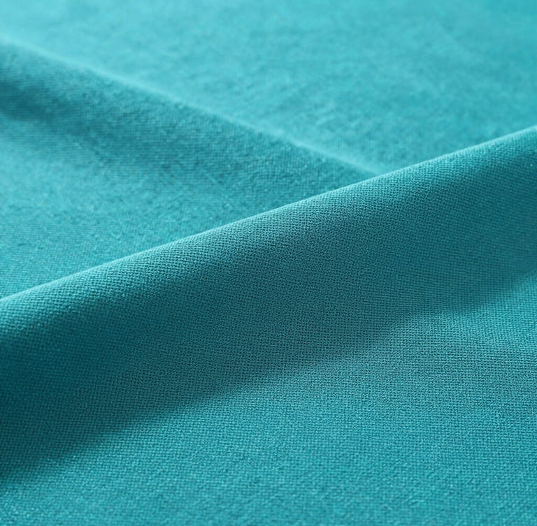 Close-up macro shot of teal cold spandex viscose fabric texture, showing the fine breathable weave, soft folds, clean studio lighting