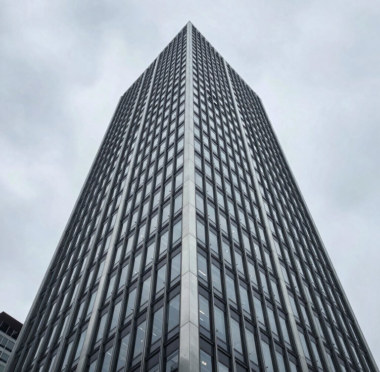 Extreme low-angle architectural shot of a brutalist steel and glass skyscraper facade rising into an overcast metropolitan sky, sharp geometric lines, cool-toned natural light.