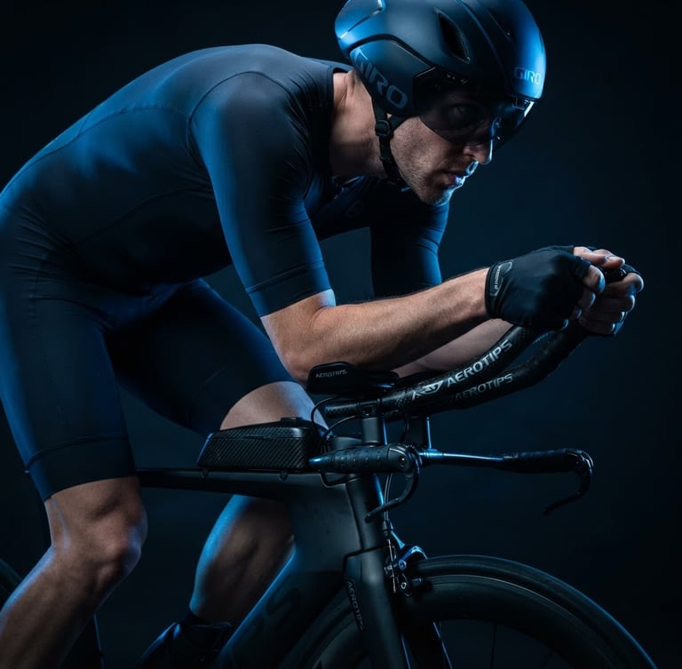 Primo piano di un triatleta PRO in posizione aerodinamica su una bici da crono, con accessori AEROTIPS ben visibili, illuminazione studio ad alto contrasto e luce di bordo blu elettrico, messa a fuoco sui dettagli tecnici.