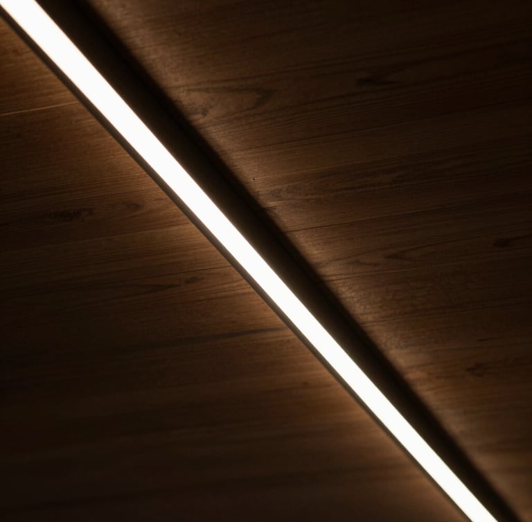 Close-up of a perfectly installed linear LED light channel in a dark wood ceiling, sharp architectural lines, warm amber glow, high-contrast shadows