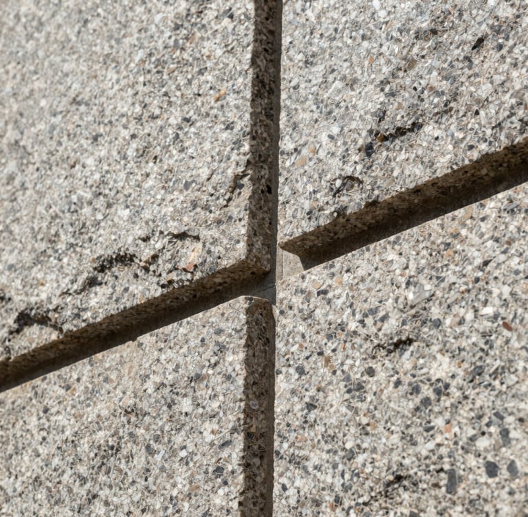 Low-angle close-up of interlocking granite stone joints, showing perfect alignment and geometric precision under bright sunlight