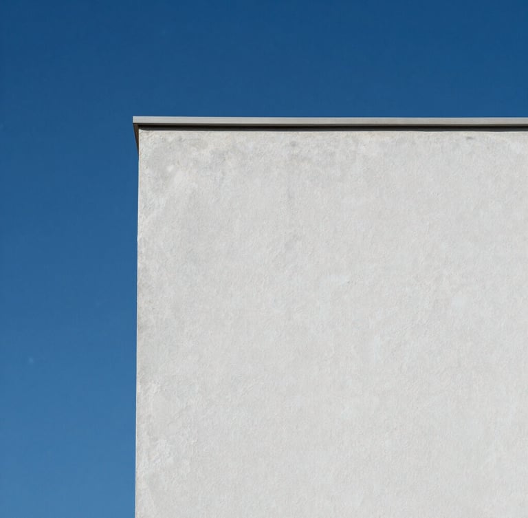 Minimalist close-up of a clean painted exterior wall texture against a deep blue sky, showing perfect matte finish and crisp architectural shadow.