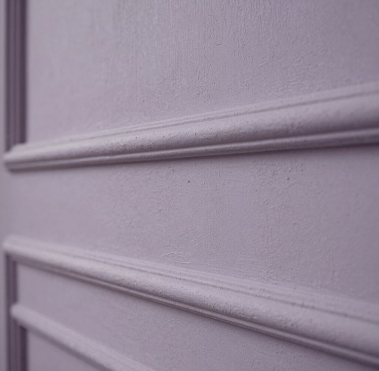 Macro photograph of hand-applied plaster texture, desaturated lavender-gray tones, soft side lighting, classical estate wall detail.