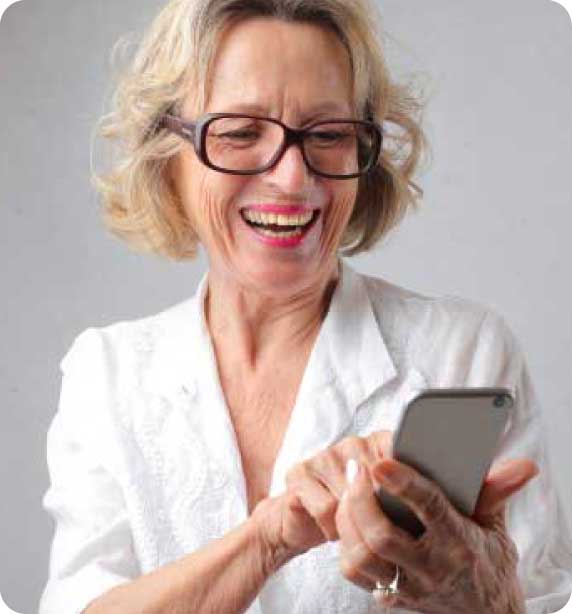 mujer mayor con gafas sonriendo mirando su smartphone