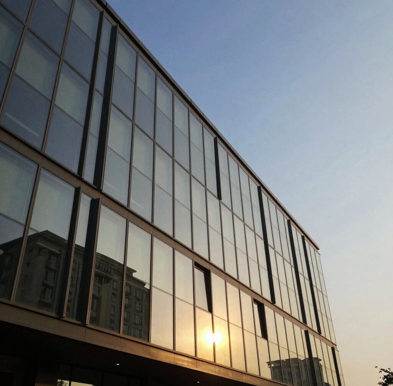 Crisp architectural geometry of DLF The Camellias glass facade reflecting golden hour light against a clear blue sky in Gurugram.