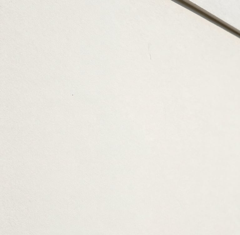 Gros plan architectural de l'angle d'un mur parfaitement lisse, peinture blanche mate uniforme, lumière rasante naturelle révélant l'absence totale de défaut