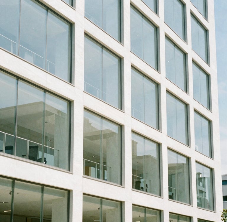 Bright daylight architectural shot of a modern clean glass office facade with sharp shadow lines, 35mm photography
