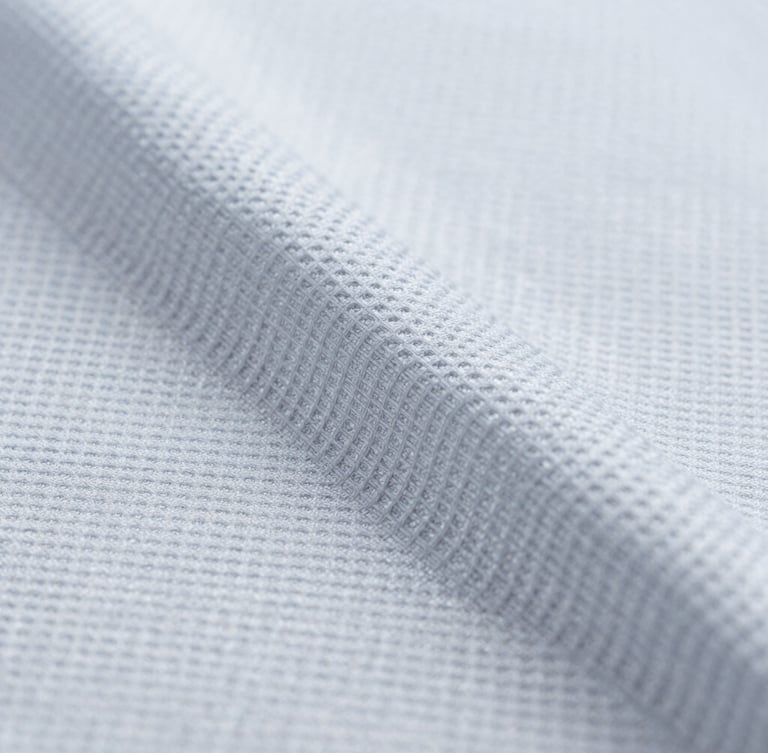 Crisp macro photograph of technical sports fabric texture, showing moisture-wicking capillary weave, bright cool-toned studio lighting, sharp focus, 50mm lens.