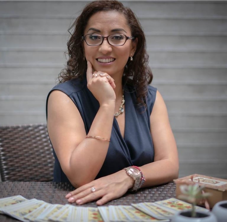 Mujer profesional de tarot sentada en una mesa con una baraja de tarot 