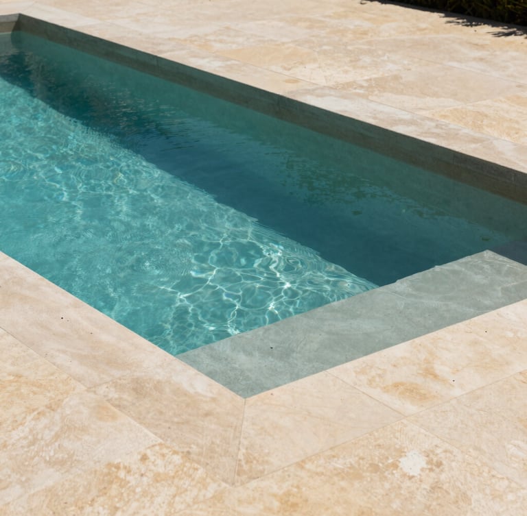 Architectural photography of a minimalist rectangular concrete swimming pool under bright Var sunlight, natural stone coping, turquoise water contrasting with warm beige stone deck.