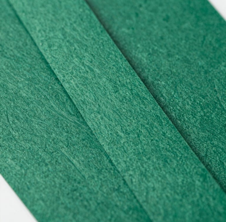 Macro close-up of freshly printed heavy-stock event lanyards showing rich paper texture and deep forest green embossing, natural side-lighting, 35mm lens