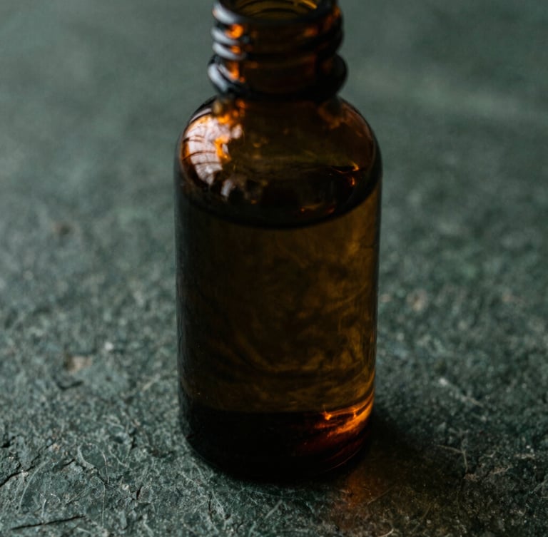 Macro overhead shot of dark amber glass apothecary bottle on a textured charcoal stone surface, rich copper-gold light catching the glass, deep forest green shadows, moody 35mm photography
