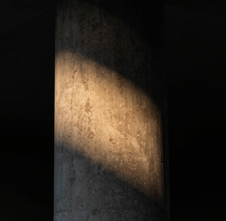 Dramatic vertical portrait of a monolithic concrete column, a sharp diagonal beam of warm amber light grazing the rough texture, deep black shadows on the left, 35mm lens