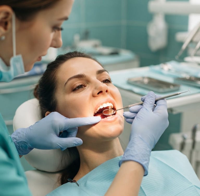 Reassuring close-up of a dentist's gloved hands gently examining a patient's mouth under bright clinical light, sterile equipment in soft focus in background, calming teal tones.