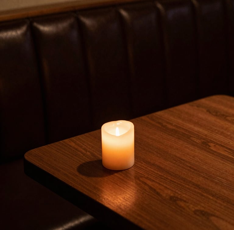 Tight macro crop of a dark leather booth corner, warm amber candle light casting deep shadows on a polished wood table, moody atmosphere.