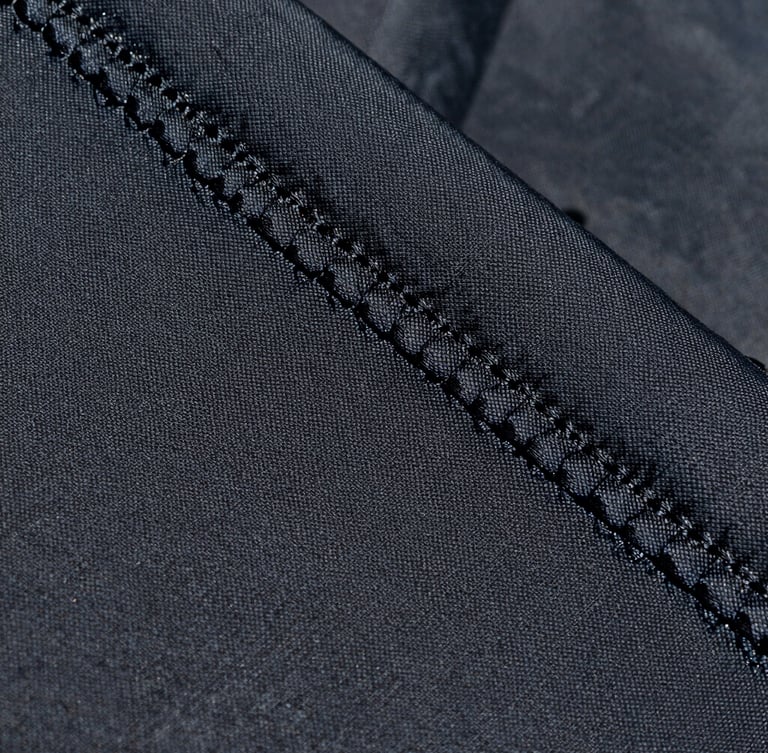 Close-up macro shot of double-stitched UV-stabilized polymer fabric texture under direct Abu Dhabi sunlight, highlighting the heavy-duty weave and structural integrity.
