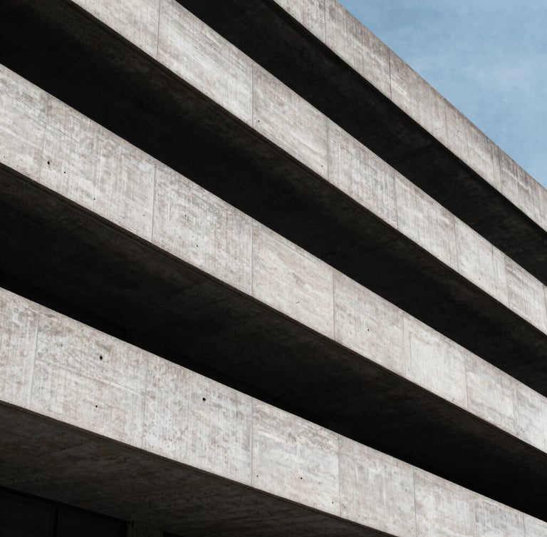 Low-angle heroic shot of brutalist London concrete architecture, hard directional daylight, deep shadows, cool gray tones, 35mm lens
