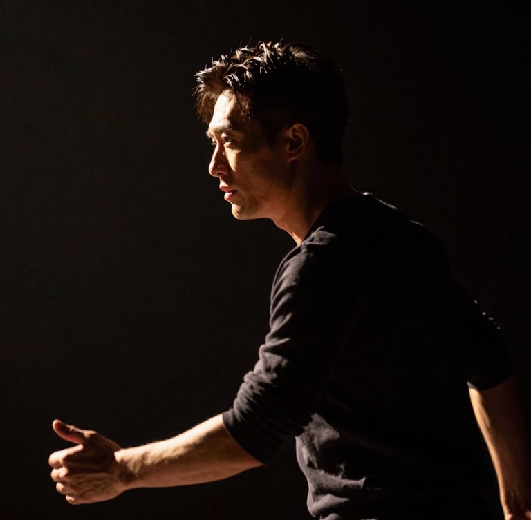 Dramatic low-key stage lighting from the side, highlighting the intense profile of an actor in motion, dark background, cinematic 16:9 framing.