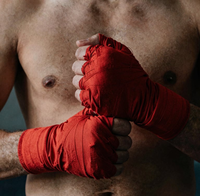 Close-up of an athlete's hands tightly wrapping in red cotton wraps before a fight, gritty side lighting, deep shadows, raw texture