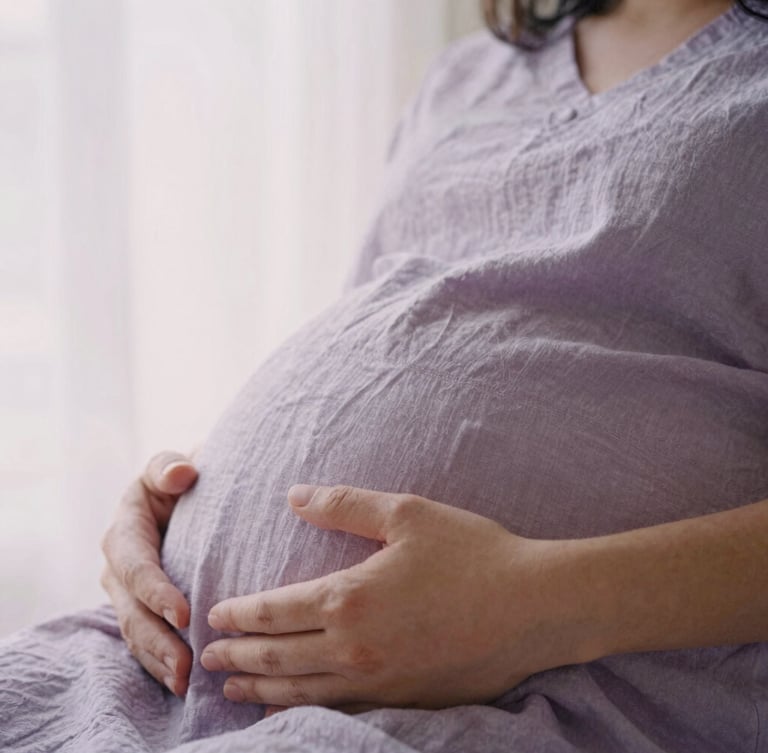 Close-up of hands resting gently on a pregnant belly, soft linen fabric, warm diffused morning window light, peaceful atmosphere, 35mm photography