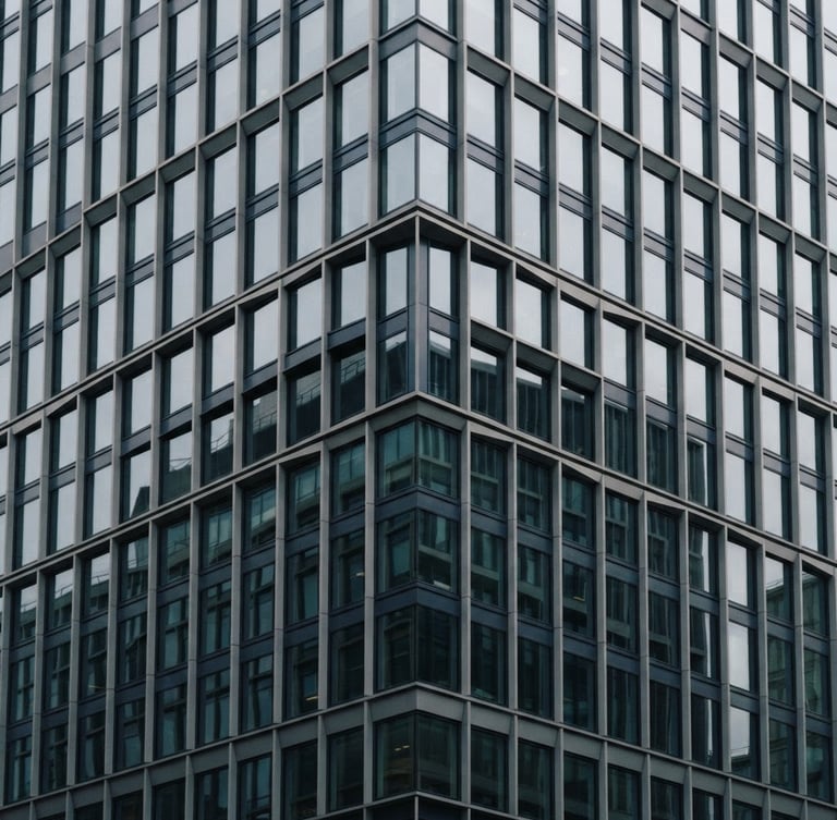 Architectural detail of a modern financial district building facade with geometric shadows, soft overcast light, muted navy and slate tones, 35mm.