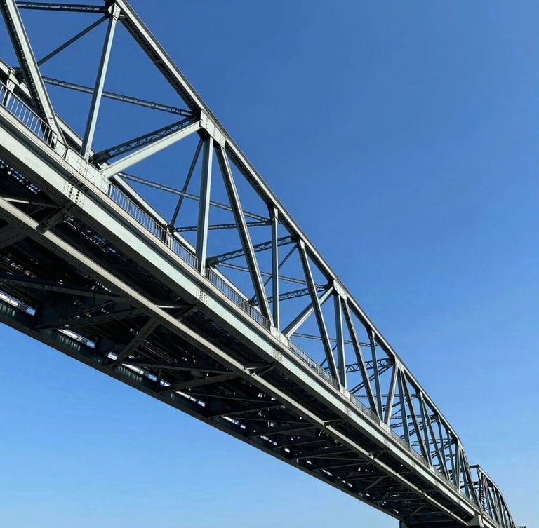 Low-angle sharp architectural photography of a massive steel bridge structure under bright high-contrast daylight, deep blue sky, metallic steel tones