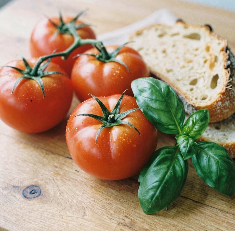 Soft natural daylight on a rustic wooden table with ripe heirloom tomatoes, fresh basil, and sourdough bread, rich crimson and forest green tones, shallow depth of field, 35mm film look