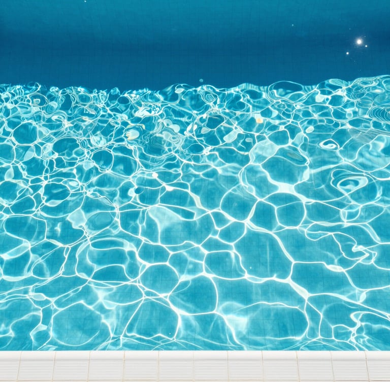 Top-down overhead shot of a swimming pool with crystal-clear cerulean water, clean white tiles, and sharp geometric shadows cast by high-noon direct sunlight