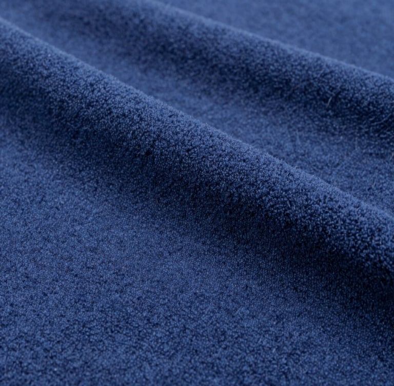 Macro photograph of heavy navy blue cotton fleece fabric, clean industrial daylight, sharp weave texture, 35mm