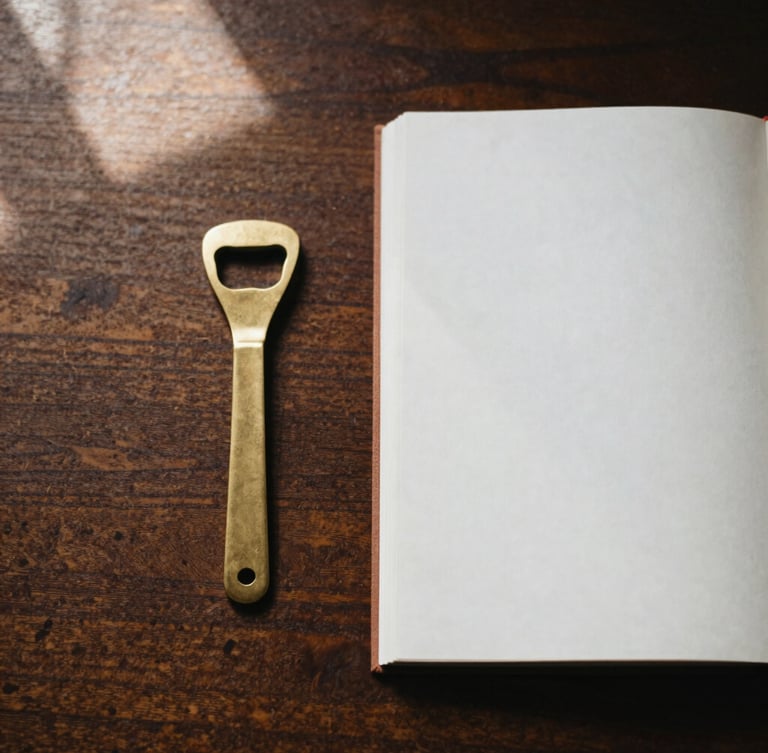 Overhead flat-lay of a brass bottle opener and a heavy paper journal on a dark oak desk, warm morning window light, soft shadows, 35mm photography