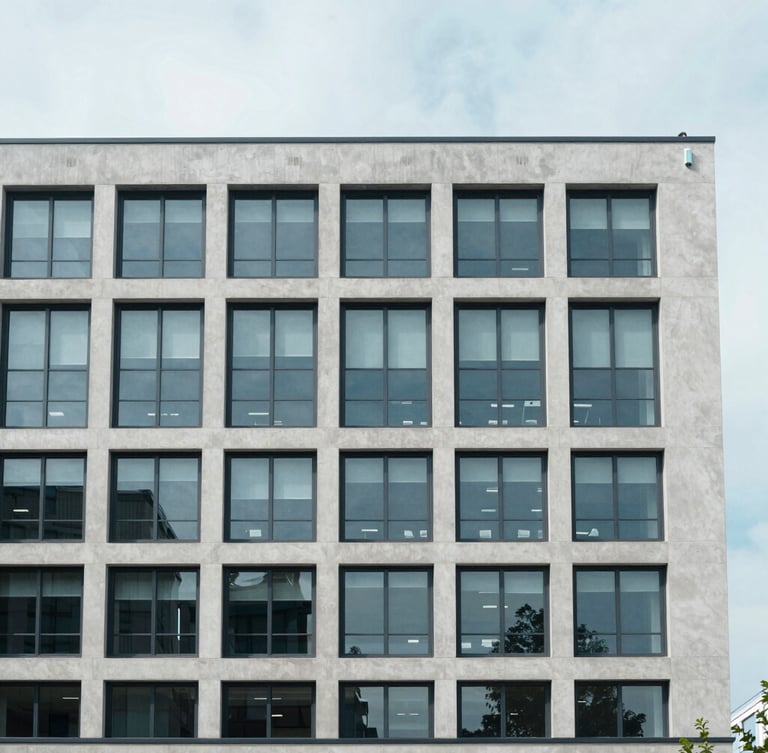 Straight-on architectural elevation of a modern commercial concrete and steel office building under bright overcast daylight, cool desaturated blue tones, sharp focus