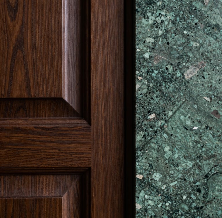 A close-up vertical shot of custom dark oak joinery meeting a rough-hewn green quartzite slab, dramatic side lighting highlighting the rich textures and recessed detailing.