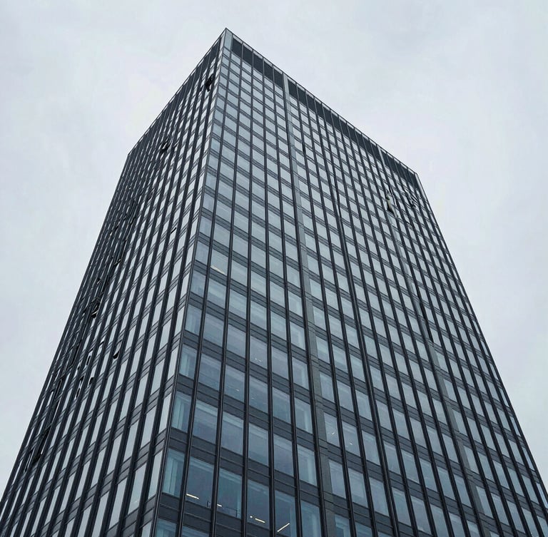 Wide-angle architectural perspective of a high-rise glass facade in Zurich, cool overcast daylight, desaturated blue and slate tones, high-contrast structural composition