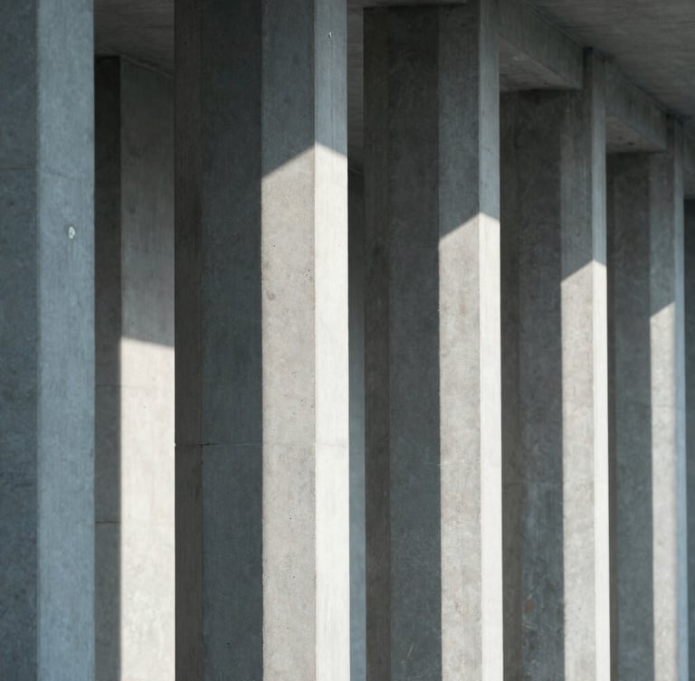 An architectural close-up of clean concrete columns and sharp, directional shadows cast by cool, diffused daylight, emphasizing structural depth and minimalist design.