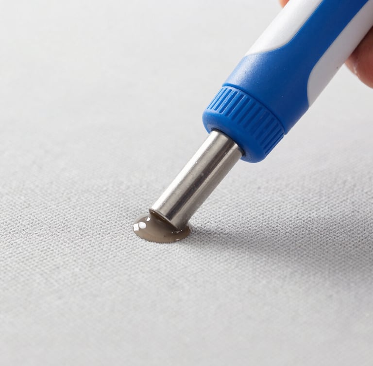 Macro close-up of a professional extraction nozzle pulling dirty water out of a light grey sofa fabric, high-key daylight, clean blue and white tones, sharp focus, professional cleaning action