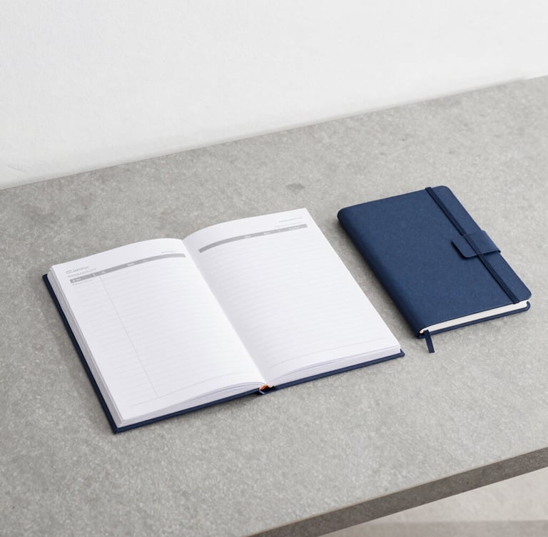 An organized minimalist workspace with a slate gray desk, a structured planner, a notebook, and clean architectural lines under bright neutral daylight