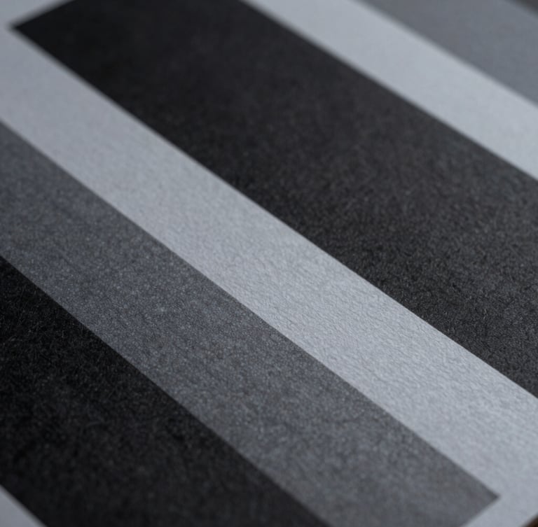 Macro close-up of high-contrast printed brand collateral, deep architectural shadows cast across textured paper grain, cool indirect daylight, minimalist composition.