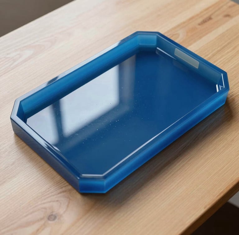 High-angle styled shot of a glossy ocean-blue resin tray resting on a light oak table, natural side-light reflecting off the glass-like surface