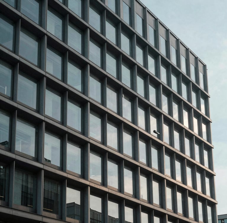 Wide panoramic architectural crop of a modern steel and concrete corporate headquarters facade, cool daylight casting soft shadows, minimal geometric structure.