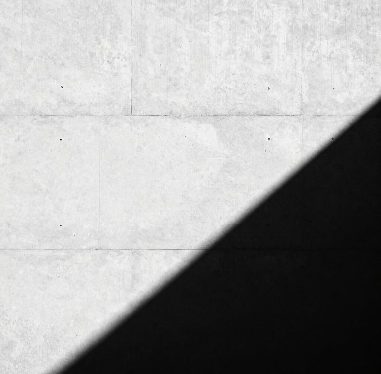 High-contrast black and white architectural photography, dramatic sharp shadows on a concrete wall, minimalist composition, 35mm lens