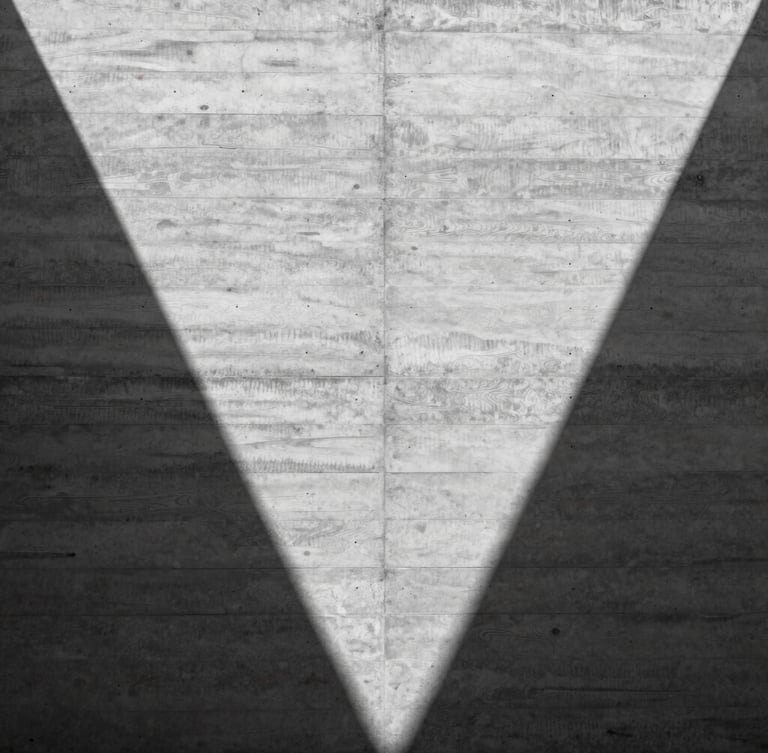 Symmetrical composition of a raw concrete wall with sharp geometric shadows, harsh midday sun highlighting timber board-marked textures, architectural detail, minimalist 35mm photography