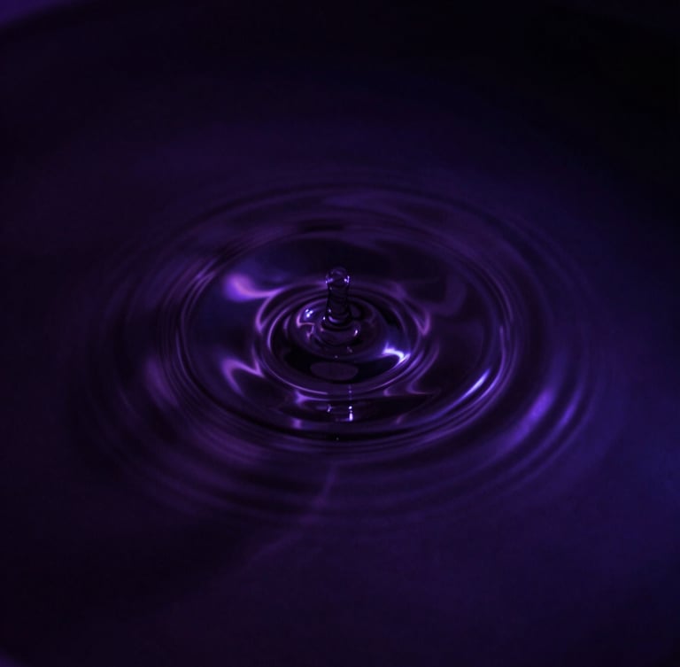 Moody dark-mode photography of a single perfect ripple expanding on dark, still water, captured with high-contrast chiaroscuro, deep violet undertones, 35mm lens, close-up.