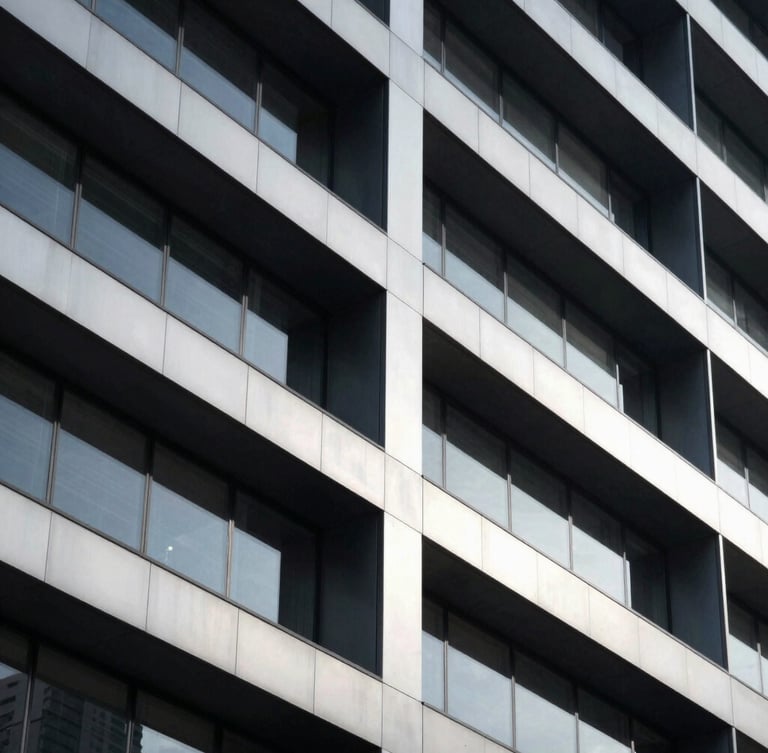 Sleek architectural photography of a modern high-end corporate headquarters facade, sharp geometric shadows, cool silver and deep obsidian tones, 35mm