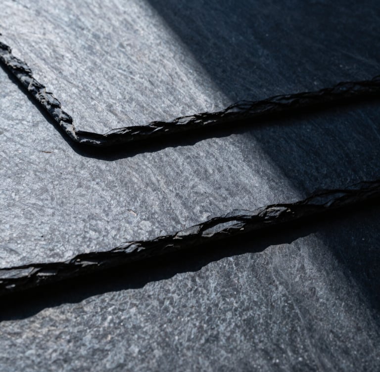 Macro architectural detail of interlocking slate panels, sharp directional light, high contrast, cool slate and deep navy tones, 35mm